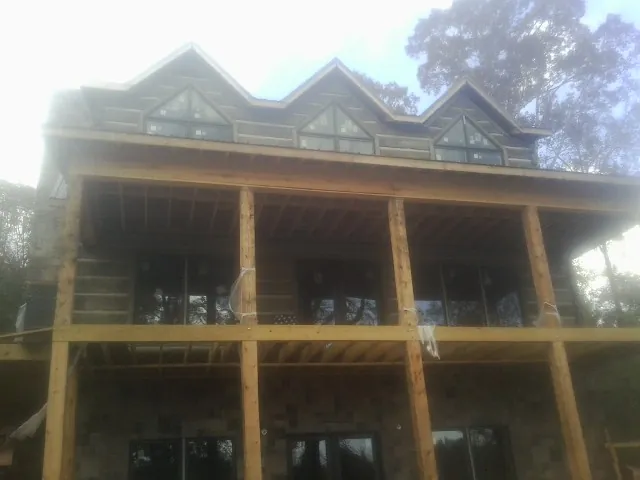 Dormers and porch framing on a large log home under construction — Roof Coating work by our crew in Freeport